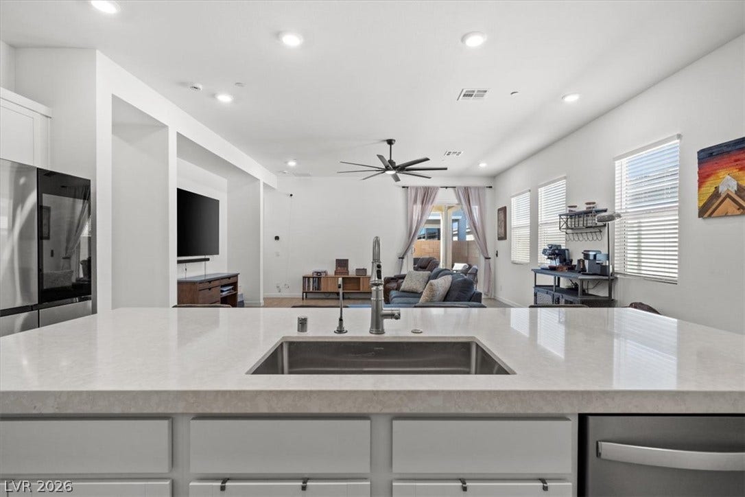 An open floorplan seamlessly connects the stone island to a spacious living area.