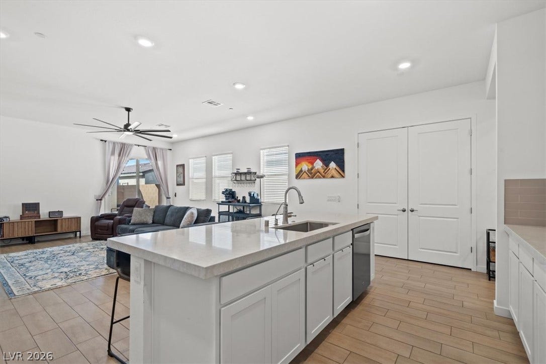 An open floorplan seamlessly connects the stone island kitchen to the bright living area.