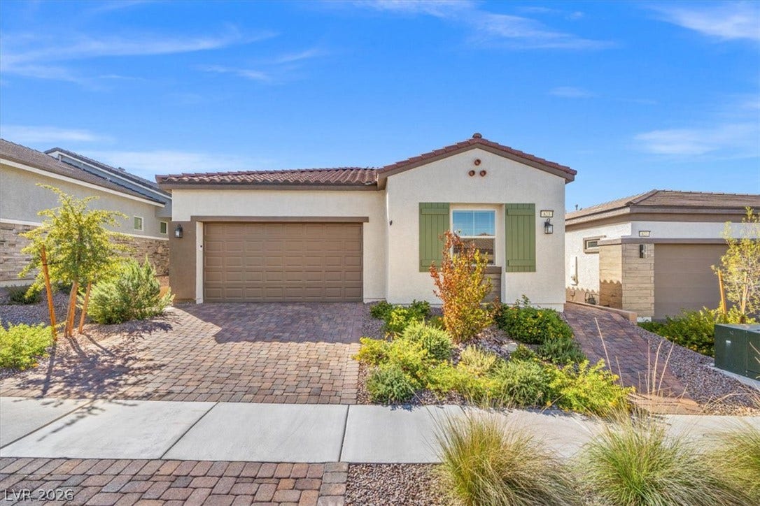 Desert landscaping and a paver driveway frame this modern single-story residence.