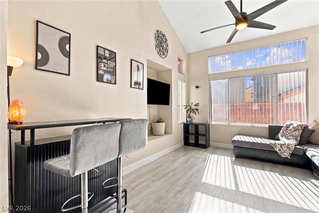 High vaulted ceilings and tall windows frame this airy open living space with wood-look flooring.