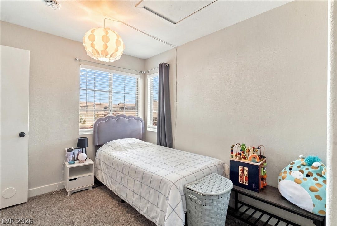 A quiet bedroom features plush carpeting and double windows overlooking the neighborhood.