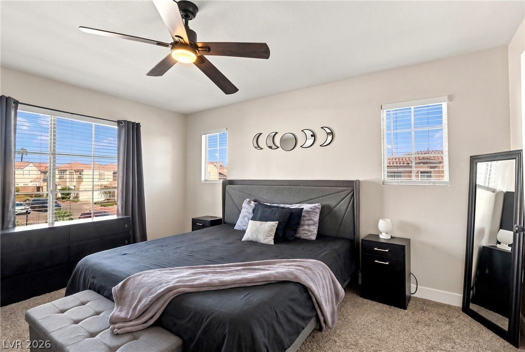 Multiple windows invite abundant natural light into this carpeted bedroom.
