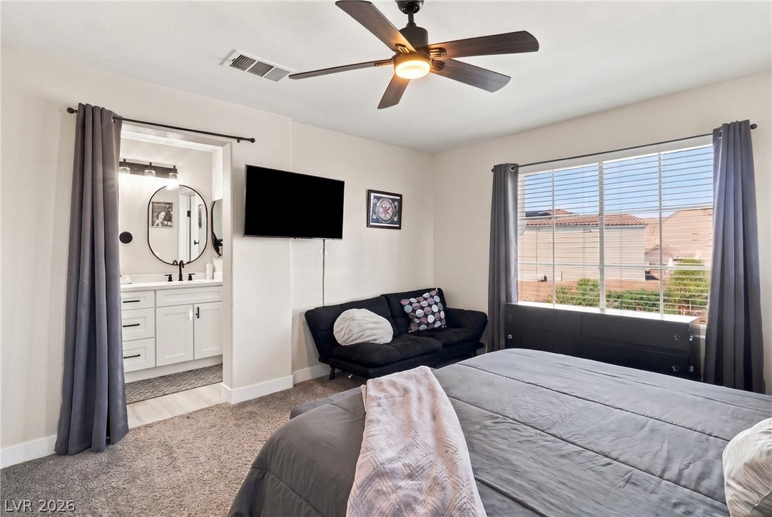 Natural light streams through a large window, illuminating the spacious master suite.