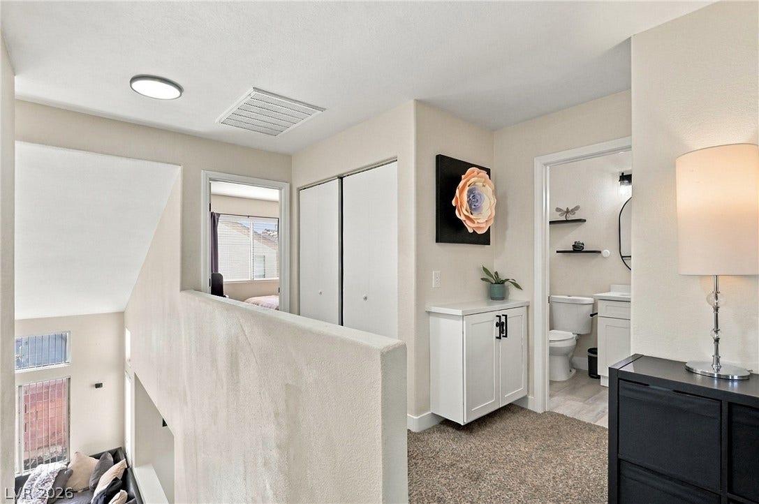 An upper landing opens to a functional layout featuring neutral carpet and built-in storage cabinets.