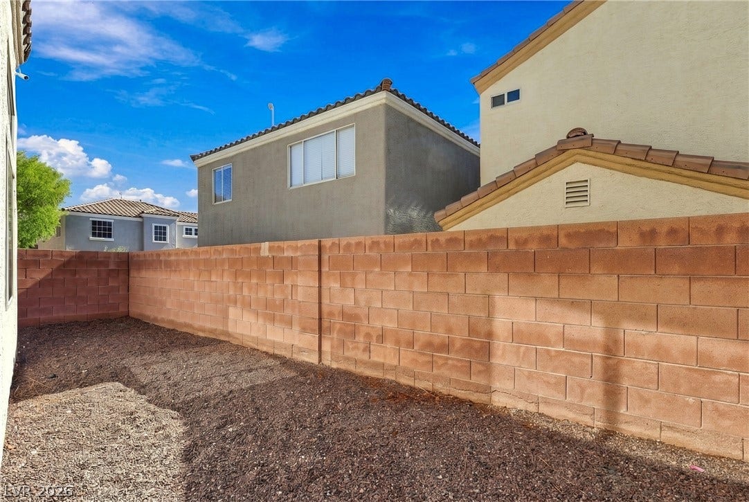A high block wall encloses this low-maintenance yard under open skies.