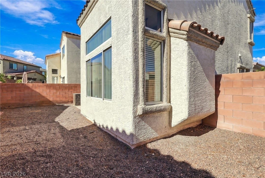 Low-maintenance gravel landscaping surrounds this stucco home featuring a tiled roof line.