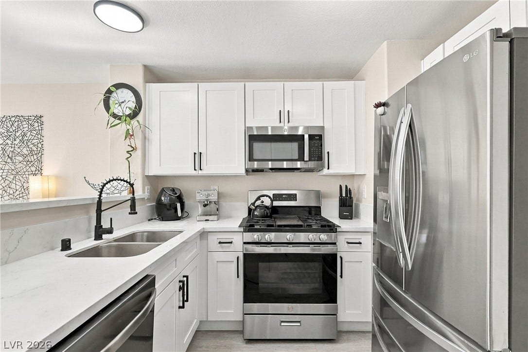 Crisp white cabinetry paired with stone countertops defines this efficiently designed cooking space.