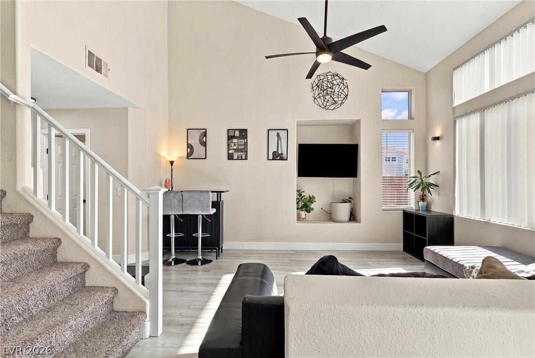 Vaulted ceilings and vinyl plank flooring define this airy living space with tall windows.