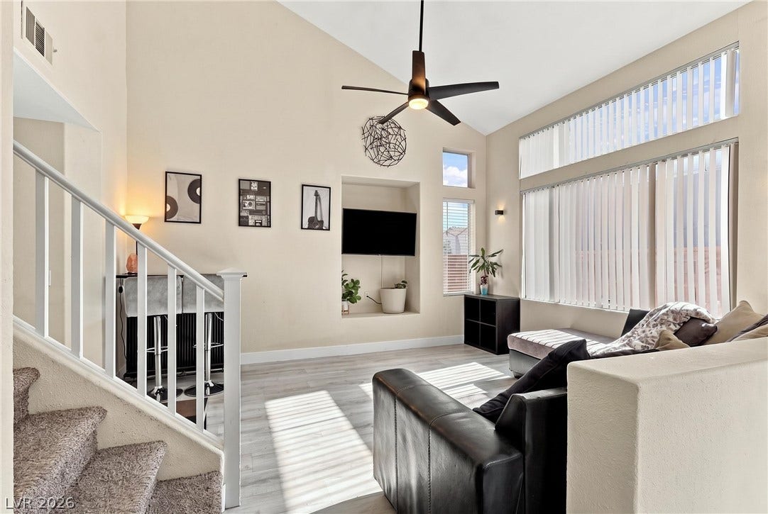 High vaulted ceilings and tall windows frame this inviting living space next to the staircase.