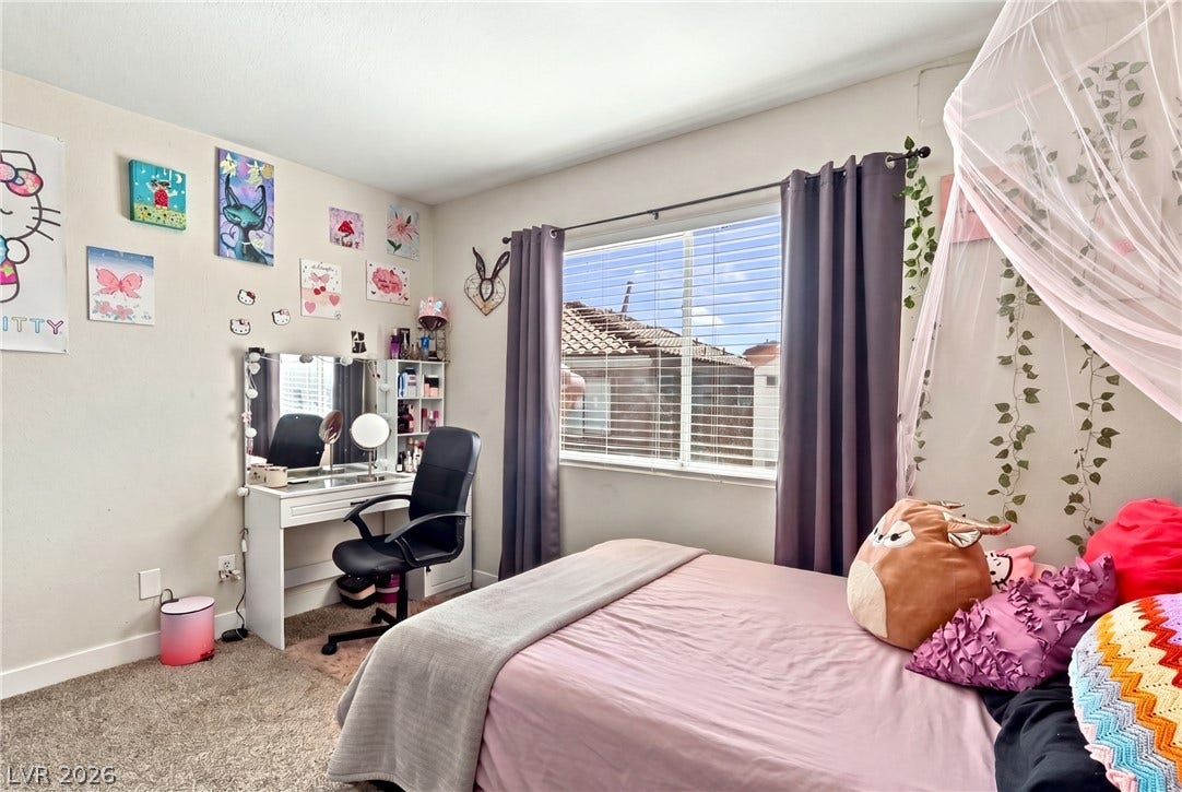 Natural light streams through a wide window, highlighting the wall-to-wall carpeting.
