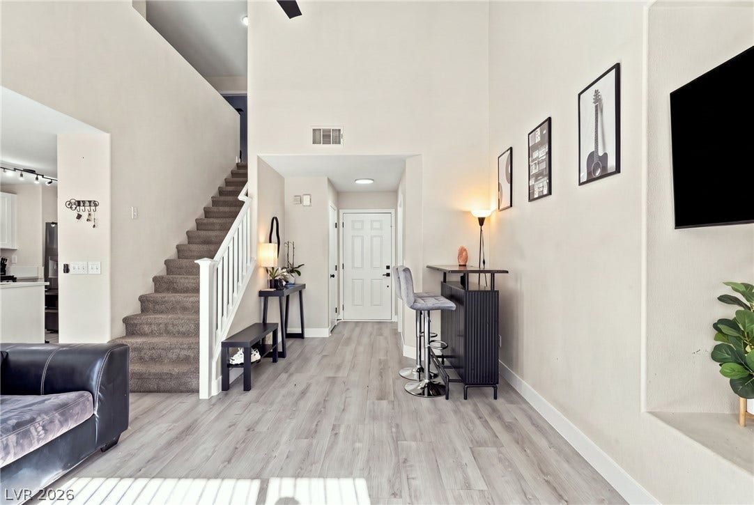 A soaring double-height ceiling and durable wood-look flooring welcome guests inside this open entry foyer.