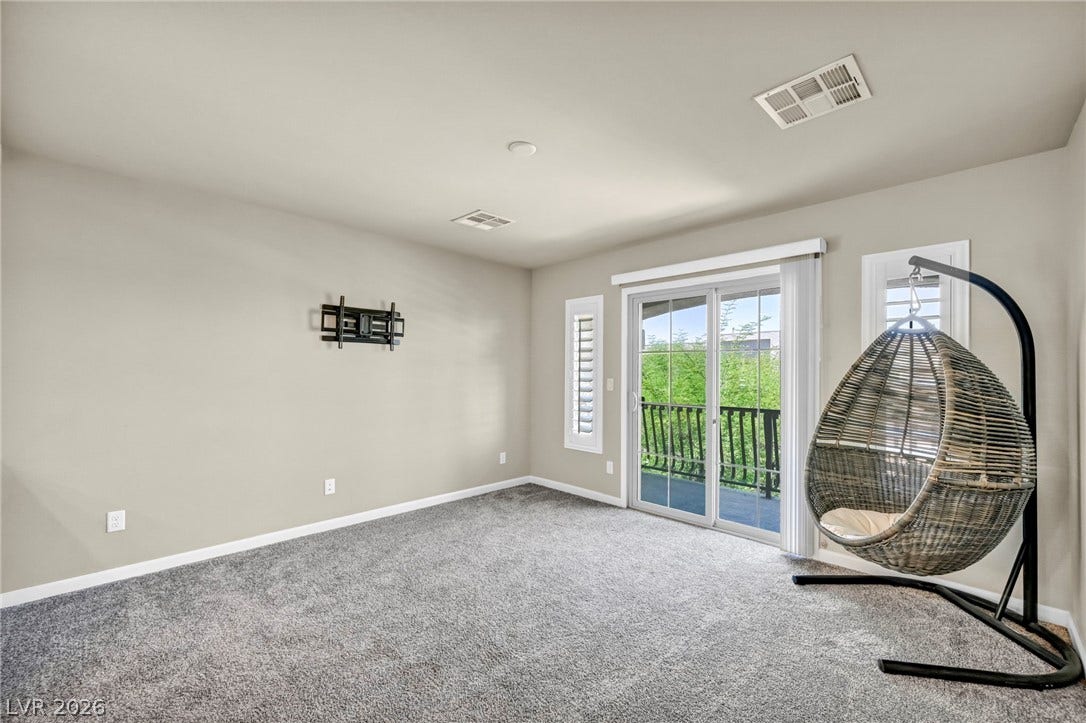 6571 Tangled Vines Avenue, Las Vegas, NV 89139 Sliding glass doors open directly to a private balcony from this carpeted living space.
