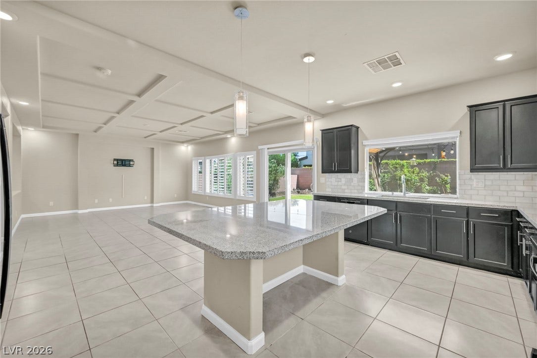 6571 Tangled Vines Avenue, Las Vegas, NV 89139 Gleaming tile floors and a generous granite island anchor this airy open-concept kitchen.