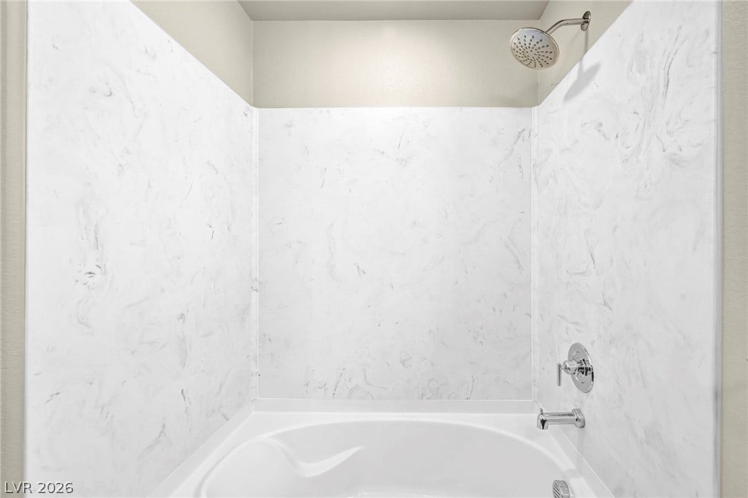 6571 Tangled Vines Avenue, Las Vegas, NV 89139 A modern soaking tub features elegant marble-look surround walls and gleaming chrome fixtures.