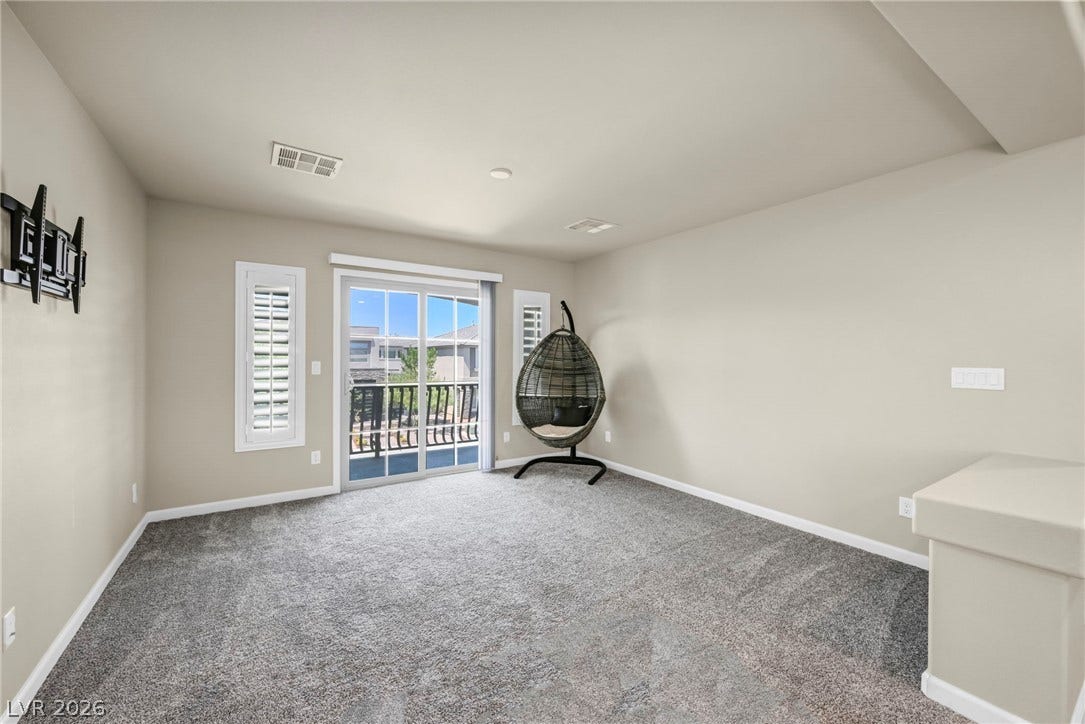 6571 Tangled Vines Avenue, Las Vegas, NV 89139 Glass sliding doors open to a private balcony from this carpeted living space.