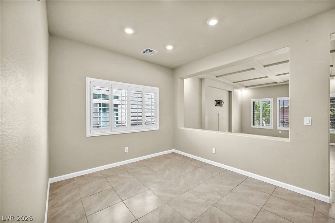 6571 Tangled Vines Avenue, Las Vegas, NV 89139 Tiled flooring and plantation shutters define this versatile room with a half-wall cutout.