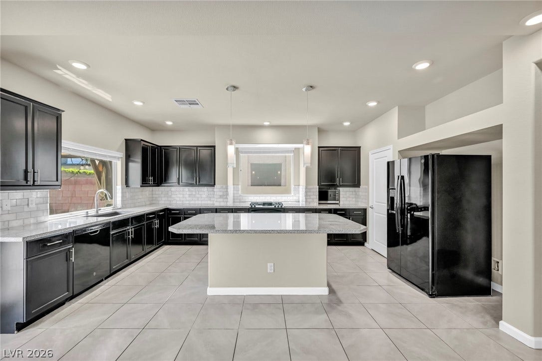 6571 Tangled Vines Avenue, Las Vegas, NV 89139 Dark cabinetry and granite countertops frame a spacious central island set on tiled floors.
