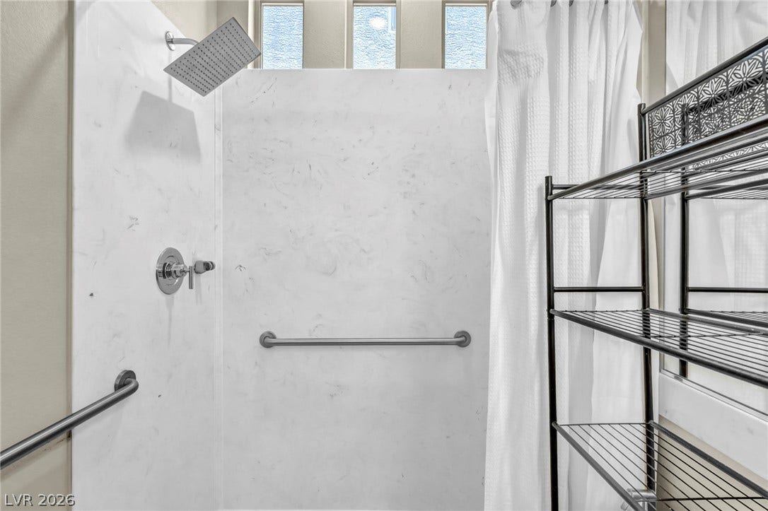 6571 Tangled Vines Avenue, Las Vegas, NV 89139 High clerestory windows bring natural light into a modern walk-in shower with stone-look surround.