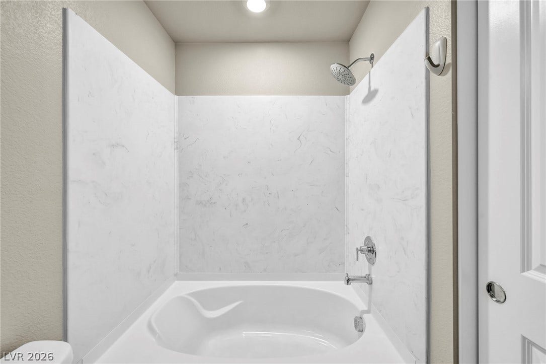 6571 Tangled Vines Avenue, Las Vegas, NV 89139 Marble-patterned paneling surrounds a deep soaking tub and shower combination.