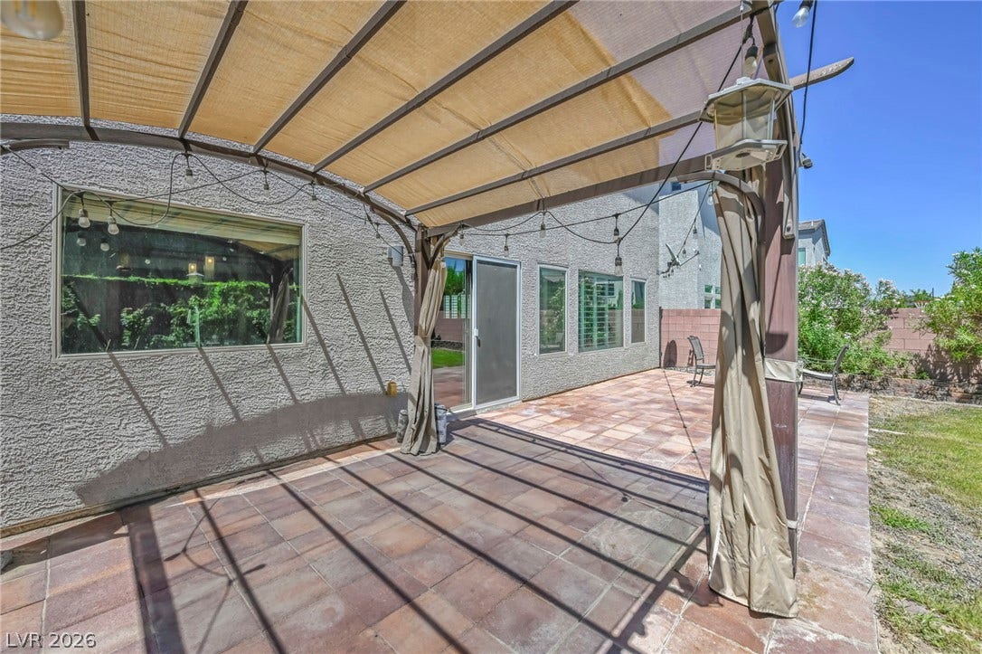 6571 Tangled Vines Avenue, Las Vegas, NV 89139 Tiled patio spaces unfold under a protective cover, bordering a grassy yard area.