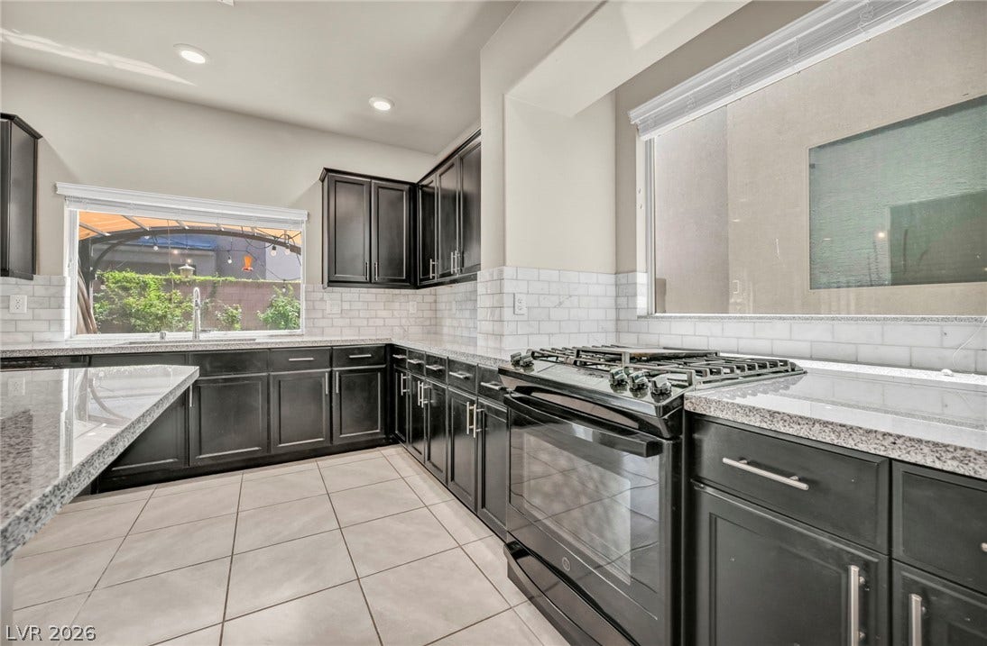 6571 Tangled Vines Avenue, Las Vegas, NV 89139 Dark cabinetry and granite countertops frame this kitchen overlooking the backyard.