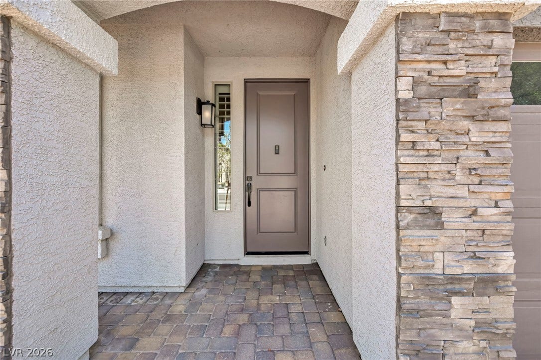 6571 Tangled Vines Avenue, Las Vegas, NV 89139 An inviting recessed entryway features textured stucco walls, stone accents, and paved flooring.