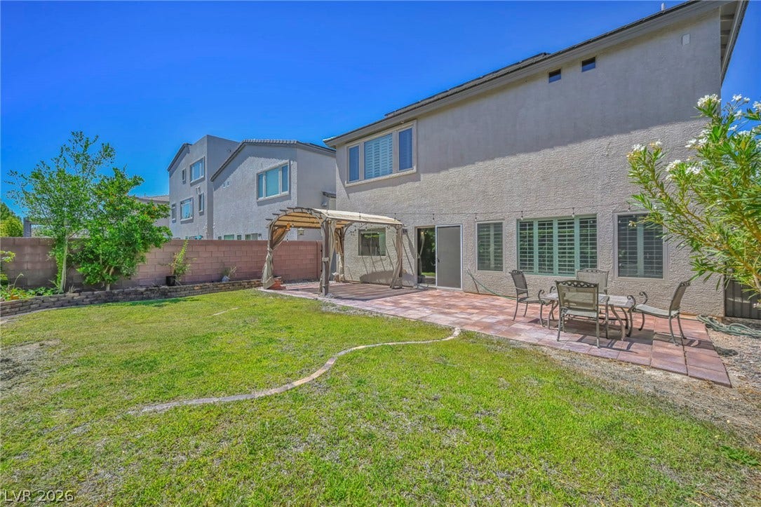 6571 Tangled Vines Avenue, Las Vegas, NV 89139 An inviting backyard features a spacious patio alongside a well-kept lawn under open skies.
