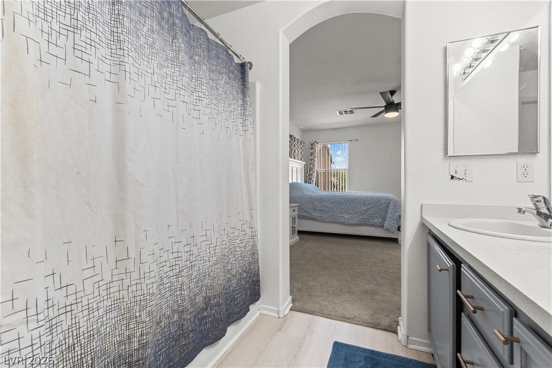 5015 Droubay Drive, Las Vegas, NV 89122 An arched doorway connects the sleek vanity area to an adjacent carpeted bedroom suite.