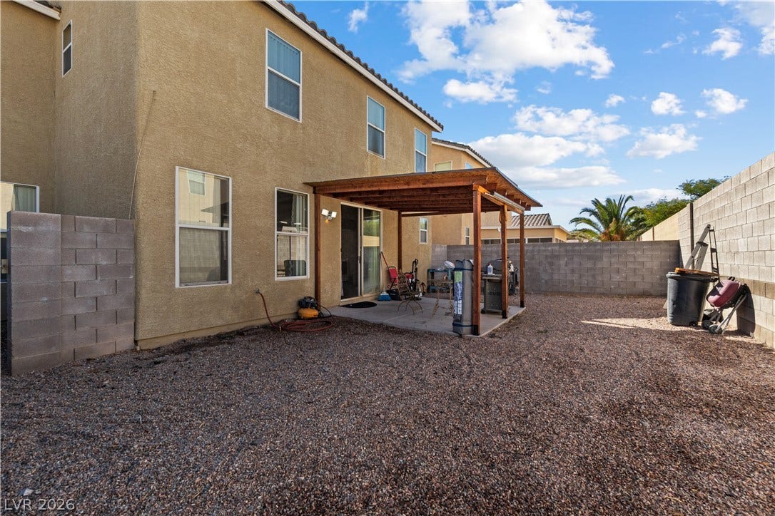 5015 Droubay Drive, Las Vegas, NV 89122 A gravel yard features a concrete patio underneath a sturdy wooden pergola structure.