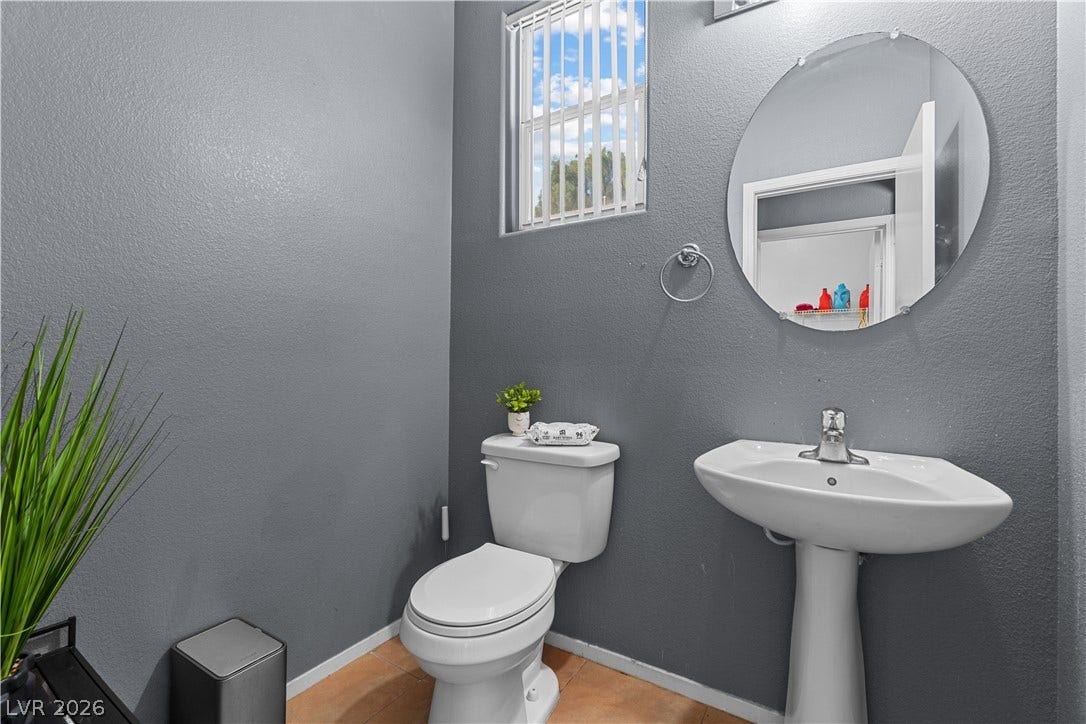 5015 Droubay Drive, Las Vegas, NV 89122 A classic pedestal sink and circular mirror accent this well-lit powder room.
