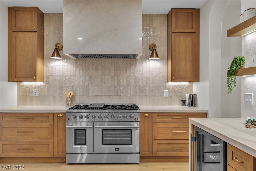 2734 Cherrydale Falls Drive, Henderson, NV 89052 Warm wood cabinetry and stone countertops frame a high-end gas range with a custom hood.