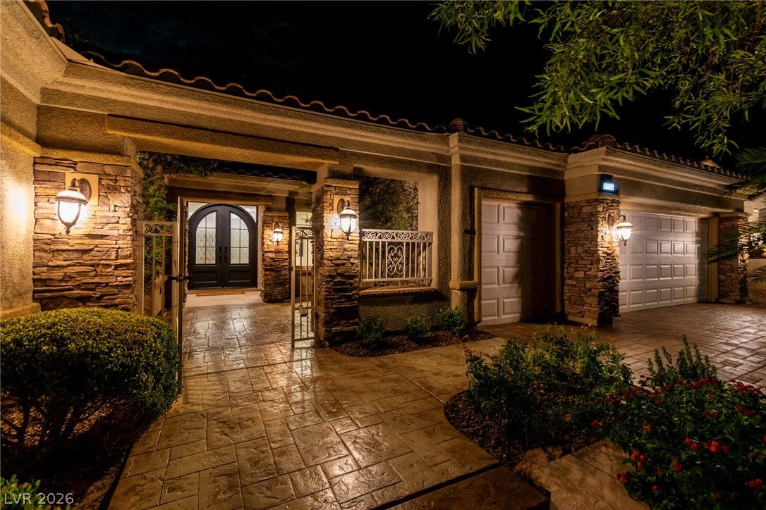 2734 Cherrydale Falls Drive, Henderson, NV 89052 Dramatic night lighting highlights the stone accents and gated entry of this elegant exterior.