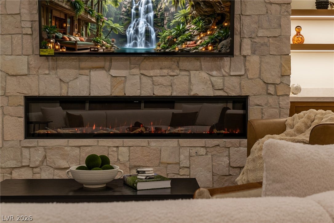 2734 Cherrydale Falls Drive, Henderson, NV 89052 A modern linear fireplace is set into a floor-to-ceiling stone accent wall.