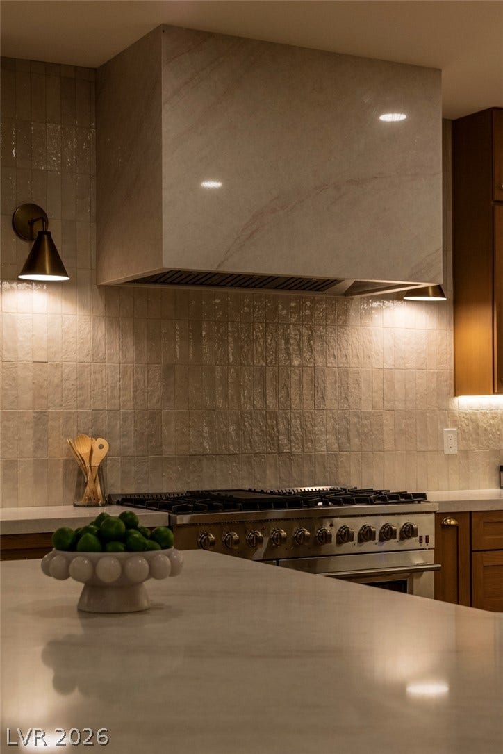2734 Cherrydale Falls Drive, Henderson, NV 89052 Glazed vertical tiles complement a custom stone-clad range hood over the professional gas range.