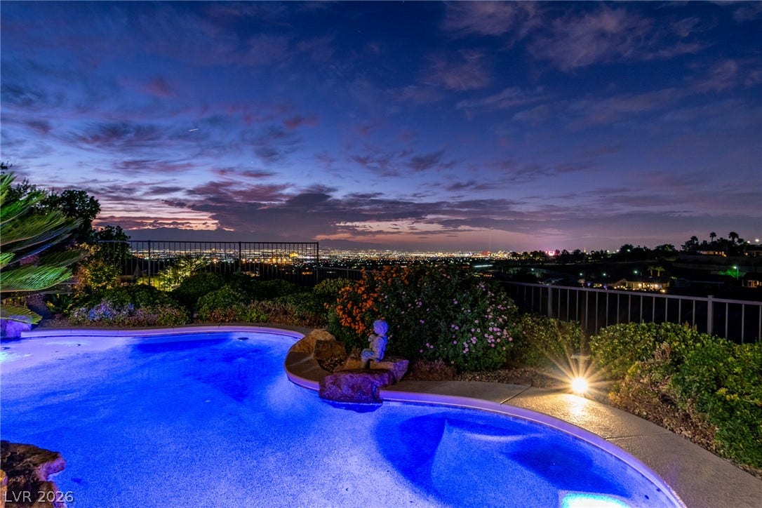 2734 Cherrydale Falls Drive, Henderson, NV 89052 A sparkling swimming pool overlooks distant city lights and mountain ridges under a twilight sky.