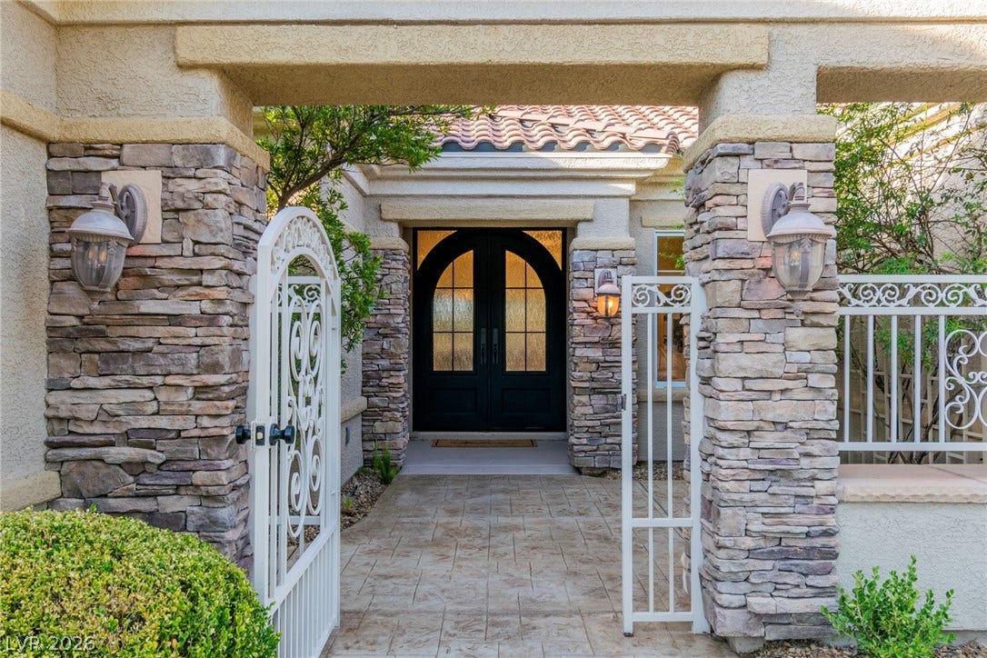 2734 Cherrydale Falls Drive, Henderson, NV 89052 Textured stone pillars and arched double doors frame this inviting gated entry courtyard.