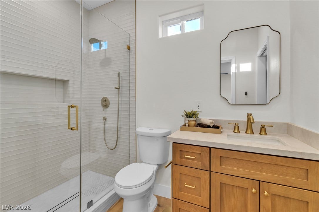 2734 Cherrydale Falls Drive, Henderson, NV 89052 A glass-enclosed shower highlights this modern washroom featuring a warm wood vanity.