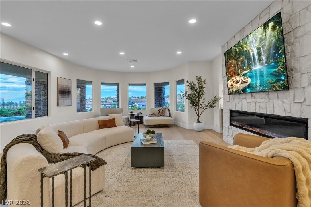 2734 Cherrydale Falls Drive, Henderson, NV 89052 An elegant stone fireplace anchors this living space, surrounded by walls of light-filled windows.