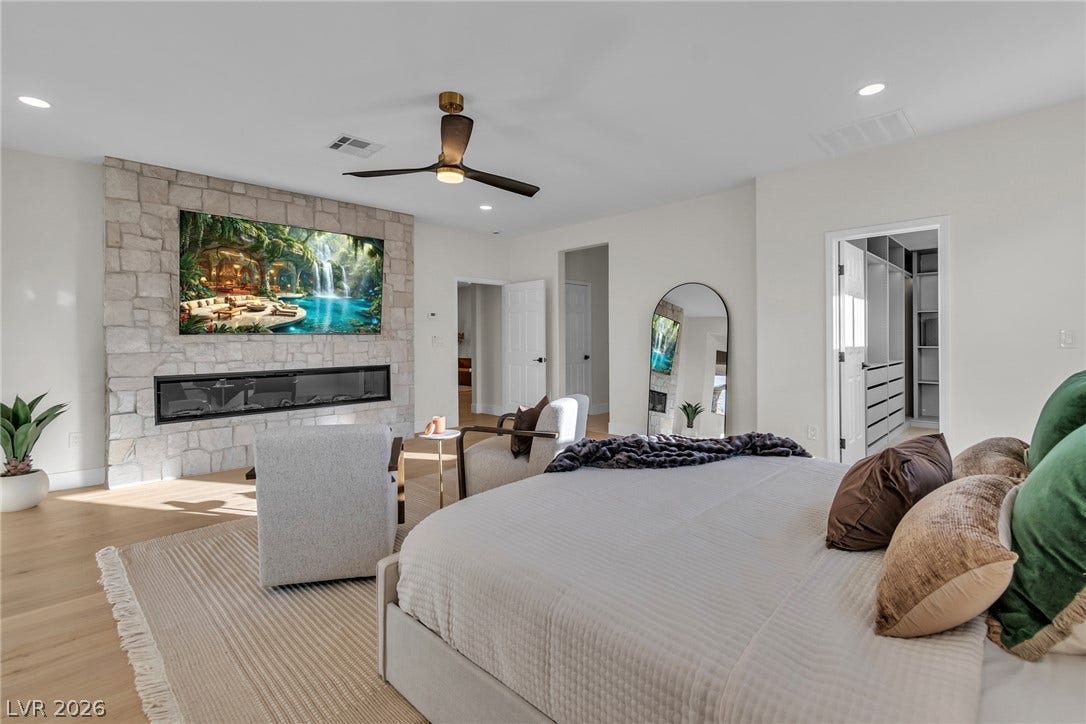 2734 Cherrydale Falls Drive, Henderson, NV 89052 An inviting stone fireplace anchors this spacious bedroom retreat with hardwood flooring.