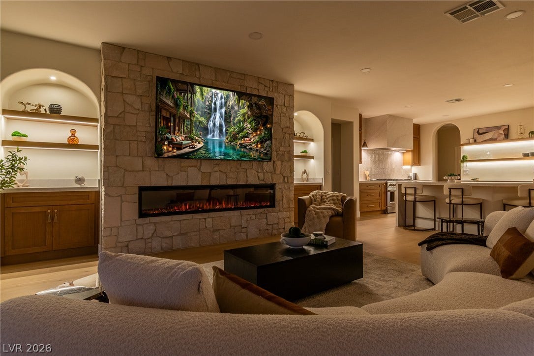2734 Cherrydale Falls Drive, Henderson, NV 89052 A stone fireplace wall commands attention in this open living space featuring wood floors.