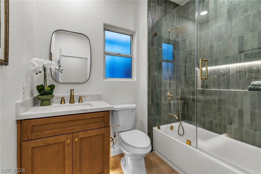 2734 Cherrydale Falls Drive, Henderson, NV 89052 Richly tiled walls and elegant brass fixtures define this beautifully updated bathroom space.