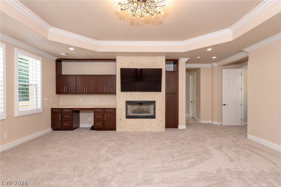 204 Satin Mist Court, Las Vegas, NV 89144 A spacious room features a tiled fireplace, built-in cabinetry, and detailed tray ceilings.