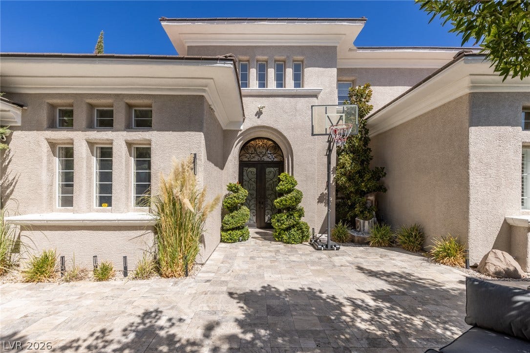 204 Satin Mist Court, Las Vegas, NV 89144 An arched wrought-iron double entryway stands out against clean stucco lines and custom stone paving.