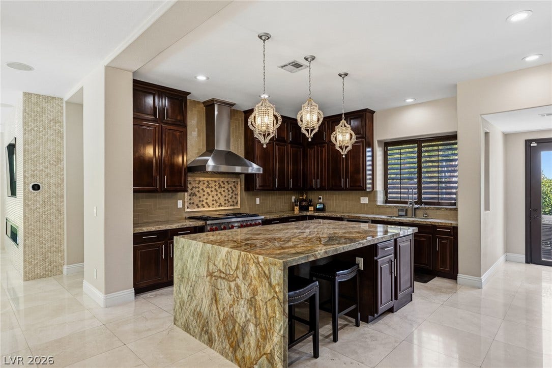 204 Satin Mist Court, Las Vegas, NV 89144 Gleaming stone countertops and dark wood cabinetry define this gourmet kitchen space.