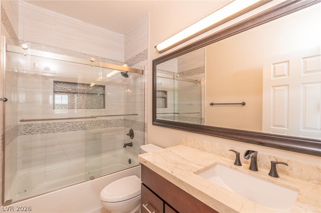 204 Satin Mist Court, Las Vegas, NV 89144 Fine stone countertops and a modern tile tub surround anchor this classic bathroom design.