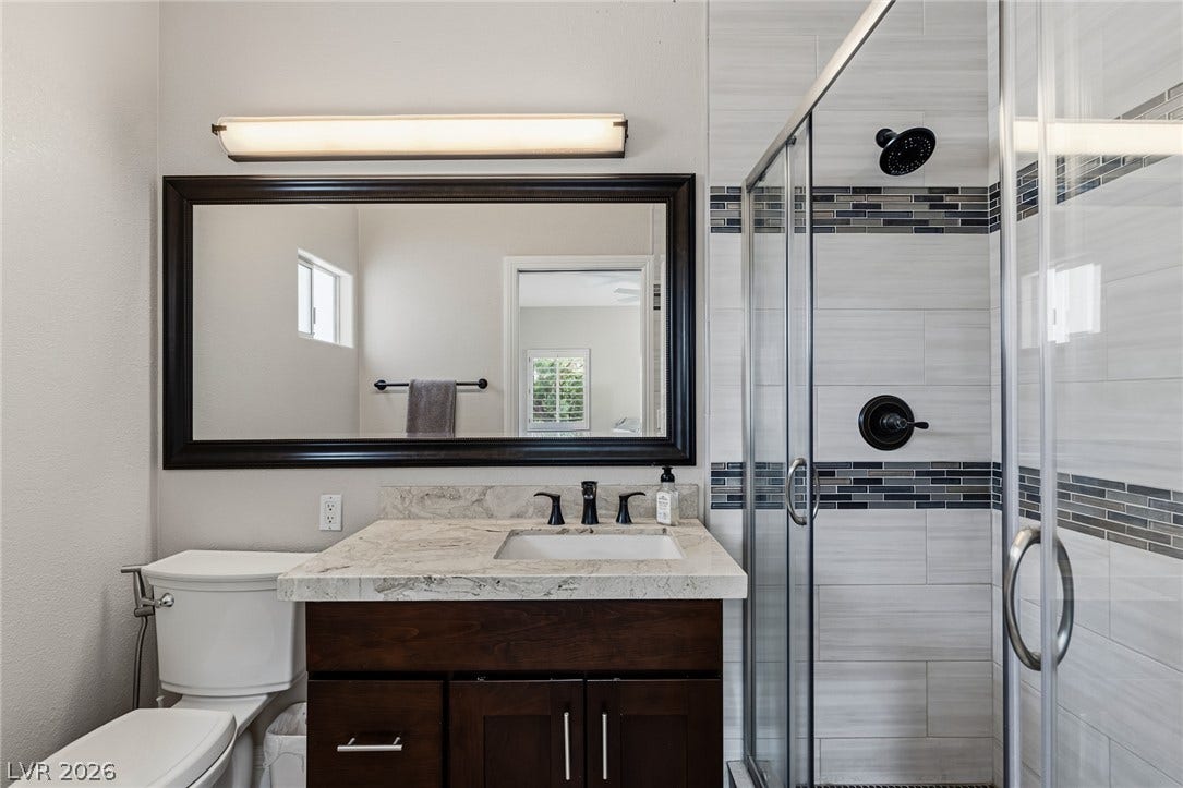 204 Satin Mist Court, Las Vegas, NV 89144 A classic dark wood vanity and tiled walk-in shower define this well-appointed bathroom.