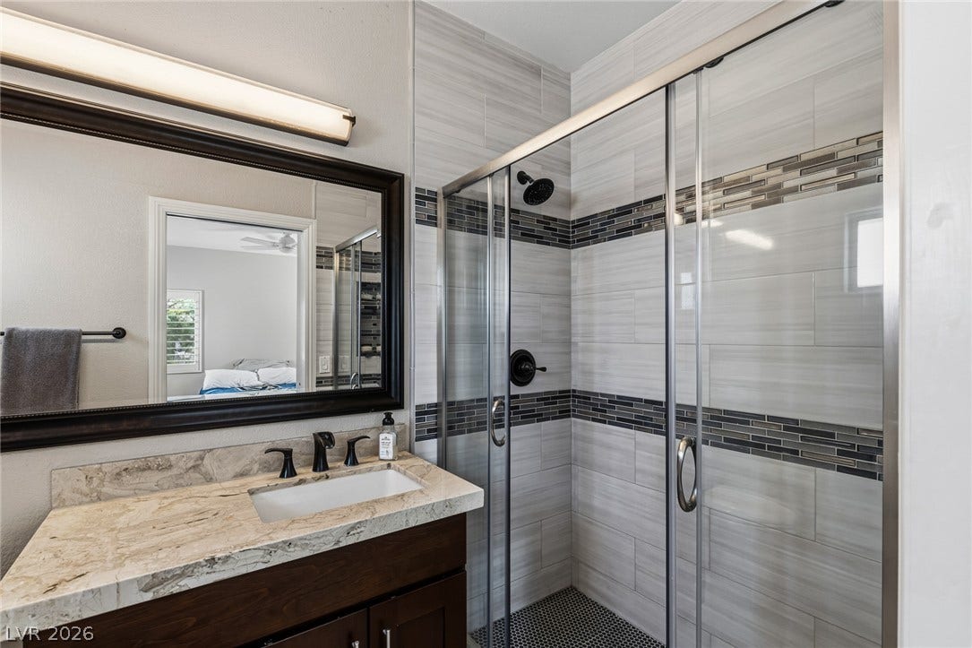 204 Satin Mist Court, Las Vegas, NV 89144 Fine stone countertops pair with an elegantly tiled walk-in shower containing glass sliding doors.