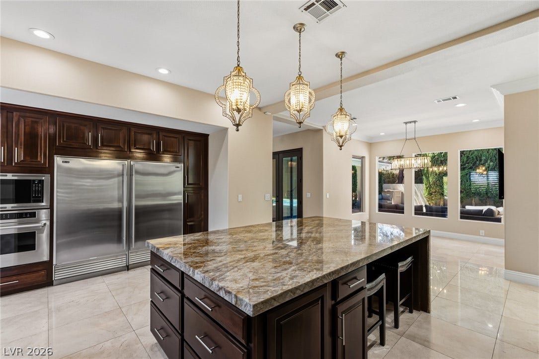 204 Satin Mist Court, Las Vegas, NV 89144 Polished tile flooring and rich wood cabinetry anchor this light-filled culinary space.