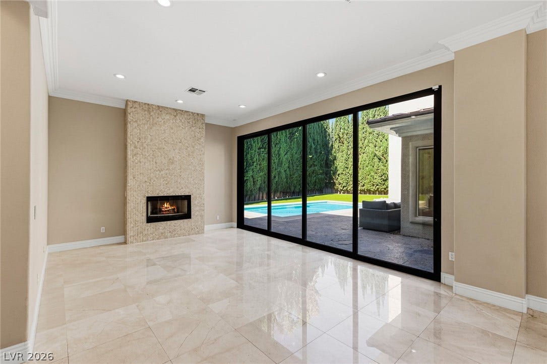 204 Satin Mist Court, Las Vegas, NV 89144 Gleaming tile floors and a modern stone fireplace frame scenic views of the backyard pool.