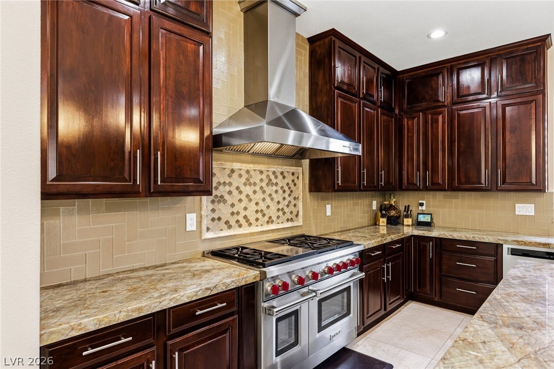 204 Satin Mist Court, Las Vegas, NV 89144 Rich wood cabinetry surrounds a professional-grade gas range beneath a stainless steel vent hood.